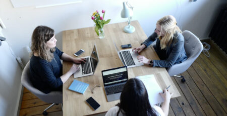 Three women working on their laptops at a table