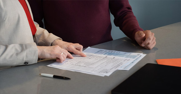 Two people seated a table reviewing paperwork together