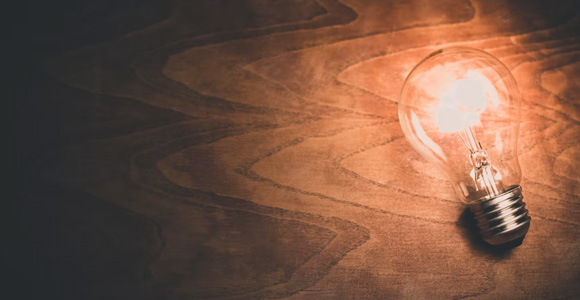 Photo of dark surface with lightbulb illuminating one side